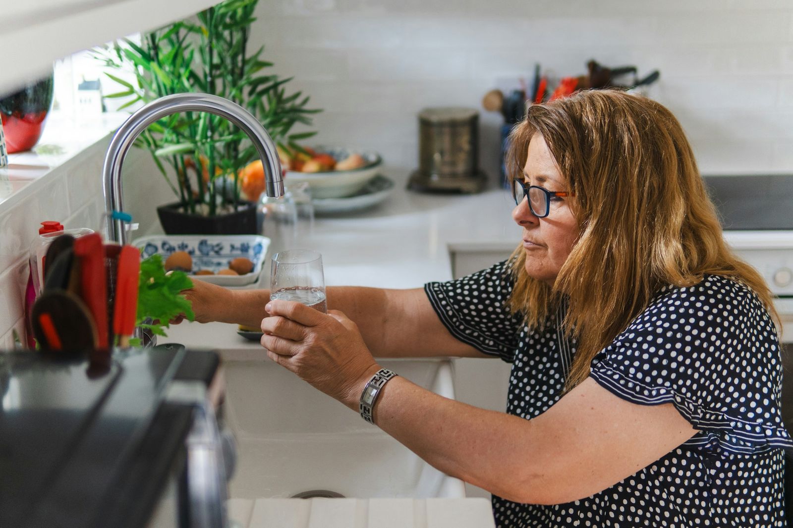 A homeowner filling a glass of clean water at her kitchen tap